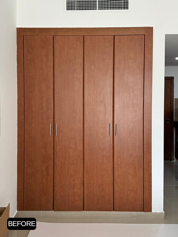 Before wardrobe wrapping in Jumeirah Village Triangle (JVT), Dubai, featuring the original brown wood built-in wardrobe before interior film installation.